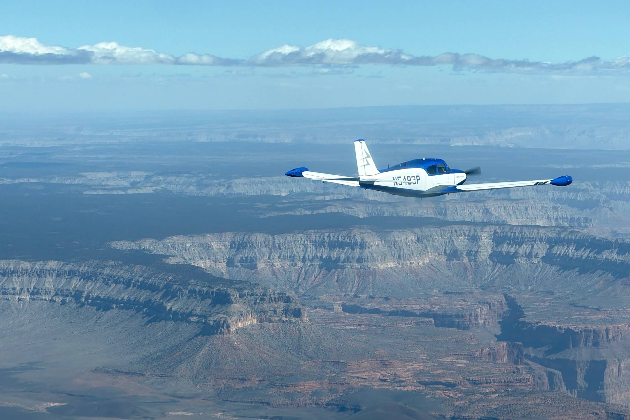 Single-engine aircraft in flight over canyon country